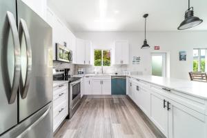 Una cocina con gabinetes blancos y un refrigerador. en Pool Boutique Villa by the Beach 1, en Hallandale Beach