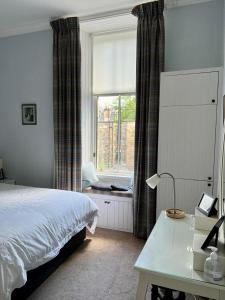 a bedroom with a bed and a window and a desk at Beautiful Double Room in Idyllic West End Townhouse in Glasgow
