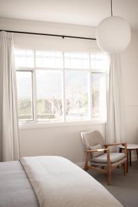 a bedroom with a bed and a chair and a window at Walton House in Huonville