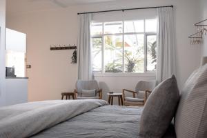 a bedroom with a bed with two chairs and a window at Walton House in Huonville