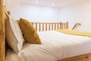 a bed with white sheets and yellow pillows at Casa do Visconde 