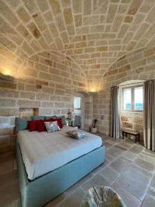 a bedroom with a large bed with a stone wall at Masseria OSTUNI MARE Agri Resort in Ostuni