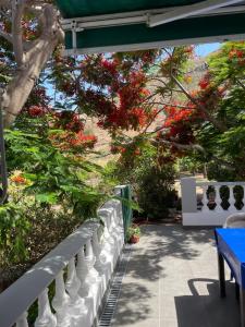 un porche con una valla blanca y flores rojas en Apartamento rural en Santa Cruz de Tenerife en Los Campitos