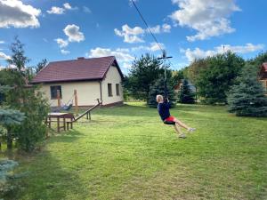 a young boy is jumping on a zip line in a yard at Leśna Oaza in Sasino
