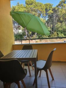 una mesa con una sombrilla verde frente a una ventana en Studio Apartment Svjetlana, en Biograd na Moru