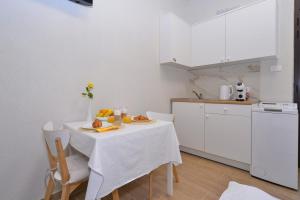 MD Studio apartman في رييكا: مطبخ أبيض مع طاولة عليها طبق من الطعام