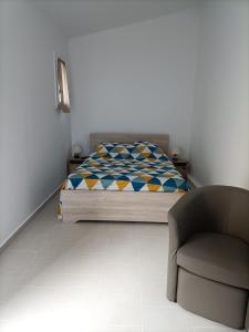 a bedroom with a bed and a chair at La Grimodière Chambre en rez de chaussée in Ranville