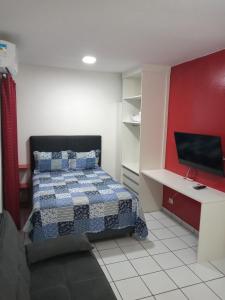 a bedroom with a bed and a desk with a television at Sala living na Av da Praia. in Santos