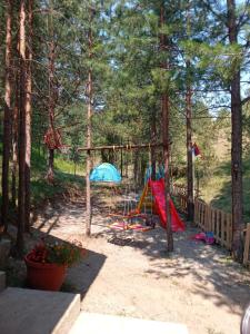 a playground with a swing set in the woods at Planinska kuca Lunjo & Vuk in Zlatibor