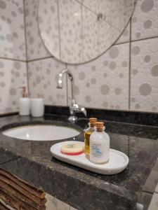 a bathroom sink with two bottles of soap on a plate at Pousada Bella Mar in Prea +55 photos
