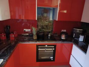 cocina con armarios rojos y horno negro en Pretty Lovely Room en Great Billing