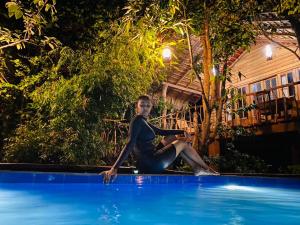 a woman sitting on the edge of a swimming pool at Habarana Tree house Mutu village in Habarana