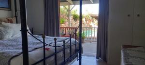 1 dormitorio con 1 cama y puerta al porche en Best Little Guesthouse -Beit Shalom, en Oudtshoorn