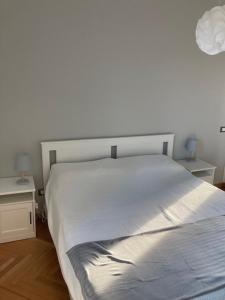 un letto bianco in una camera da letto con due tavoli di Casa dei Gelsomini a Trieste