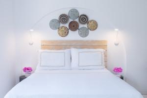 a bedroom with a white bed with plates on the wall at Yasos By The Sea in Çeşme