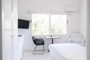 a white bedroom with a bed and a chair and a window at Yasos By The Sea in Çeşme