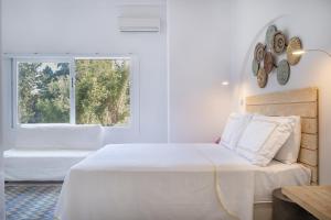 a white bedroom with a bed and a window at Yasos By The Sea in Çeşme