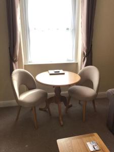a table and two chairs in front of a window at Cedar House, formerly Shamrock House in Llandudno