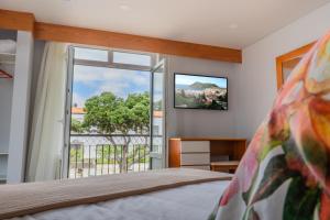 een slaapkamer met een bed en een groot raam bij Hotel Monte Brasil in Angra do Heroísmo