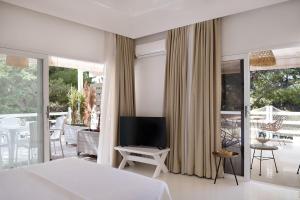 1 dormitorio con cama, TV y balcón en Yasos Suites, en Cesme