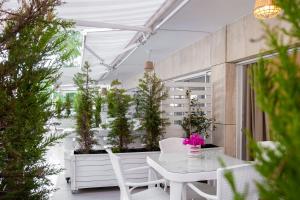 a patio with a white table and chairs and potted plants at Yasos By The Sea in Çeşme