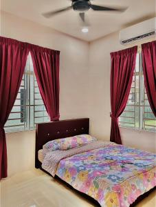 a bedroom with a bed with red curtains and a fan at HOMESTAY BANDAR KANGAR (NS FAMILY HOMESTAY) in Kangar