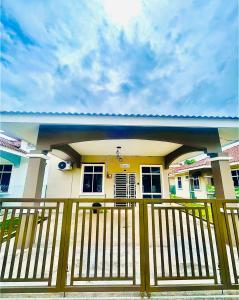 a small yellow house with a wooden fence at HOMESTAY BANDAR KANGAR (NS FAMILY HOMESTAY) in Kangar