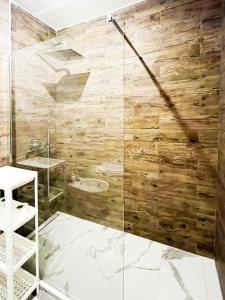 SuitesFlores - Bright and cozy apartment in Verona في فيرونا: حمام مع دش مع جدار خشبي