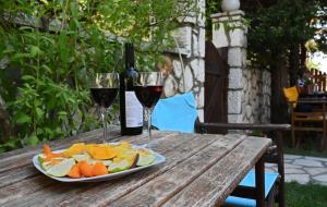 ヴァシリキにあるSanta Emeliaの木製テーブルに盛られたフルーツプレートとワイングラス