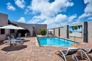 a swimming pool with chairs and an umbrella at Bubali Luxury Apartments - Adults Only - Wheelchair Friendly in Palm-Eagle Beach