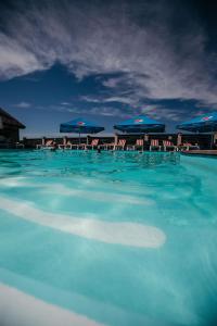 a pool of blue water with chairs and umbrellas at Chalet in Shypyntsi