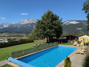 una piscina in un cortile con montagne sullo sfondo di Romantik Aparthotel Sonnleitn a Sankt Johann in Tirol