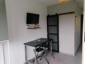 Habitación con mesa y TV en la pared. en Entre Perigueux et Bergerac en Vergt