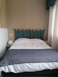 Bett mit blauem Kopfteil in einem Schlafzimmer in der Unterkunft Entre Perigueux et Bergerac in Vergt