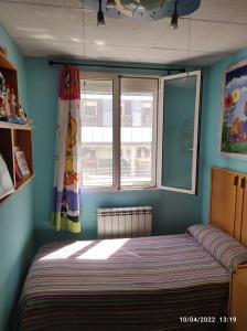 1 dormitorio con 1 cama en una habitación con ventana en Acogedor, en Zaragoza