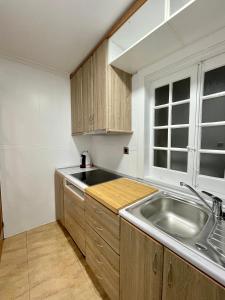 d'une cuisine avec des placards en bois, un évier et une fenêtre. dans l'établissement A Das Marias GALLERY, à Ourense