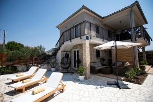 a patio with chairs and an umbrella in front of a house at Villa Marleku in Pakoštane