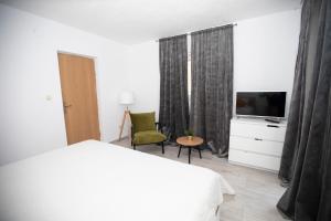 a white bedroom with a bed and a television at Villa Marleku in Pakoštane +81 photos