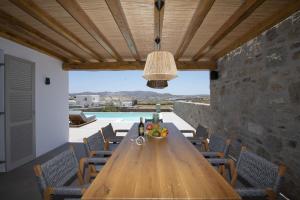 comedor con mesa de madera y sillas en Summer Breeze Luxury Villa Mykonos, en Panormos  Mykonos