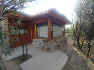 una cabaña en el bosque con una pared de piedra en Complejo Casas de Campo en San Marcos Sierras