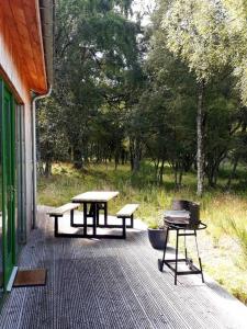 two picnic tables and a grill on a deck at Betula Chalet – coast & country in the Highlands in Nairn