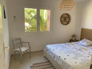 um quarto com uma cama, uma cadeira e uma janela em Saint Aygulf - a 250m de la mer- 3 pieces 45m2 em Saint-Aygulf