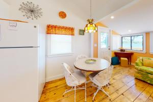 a kitchen and dining room with a table and a refrigerator at Rising Tide Cottage in Cushing