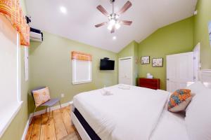 um quarto com uma cama branca e uma ventoinha de tecto em Rising Tide Cottage em Cushing