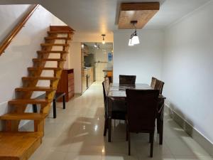 ein Esszimmer mit einem Tisch, Stühlen und einer Treppe in der Unterkunft La casa de Ely in Iquique