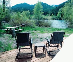 two chairs and a table on a deck next to a lake at Snake River Glamping in Irwin