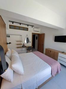 a bedroom with a large white bed and a television at Courtyard Luxury Suites “MARIANTHI” in Pefki Rhodes