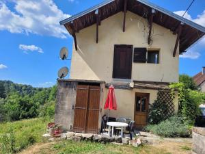 una casa en una colina con una mesa y una sombrilla en La fontaine en Vertamboz