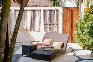 a patio with a couch and a table and trees at Villa Marina in Gili Islands