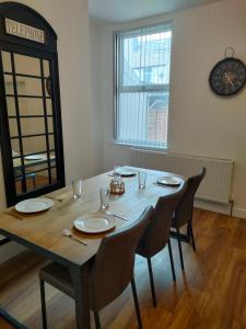 a dining room table with chairs and a clock on the wall at Lovely refurbished apartments, Morecambe Promenade in Morecambe